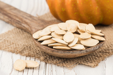 Pumpkin seeds in a wooden spoon on old wooden table.