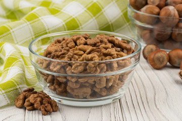 Walnuts in a glass bowl on an old white wooden table.