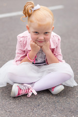 A cute little girl in a beautiful dress and sneakers playing on