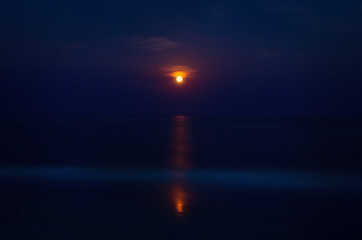 blue Night seascape with a red moon and a moonlight path