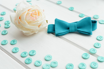 White rose, button and tie on a white wooden background