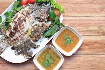 Tilapia fish grilled with Salt in white dish and have Spicy Sauc