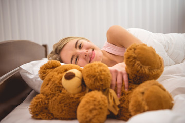 The happy woman lay on the bed with soft toy