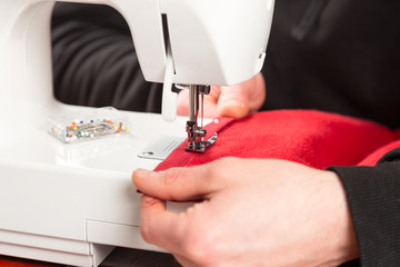 tailor at work on sewing machine with red fabric