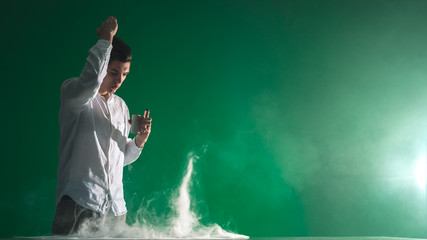 The handsome man smoke an electronic cigarette and gesture on the green background