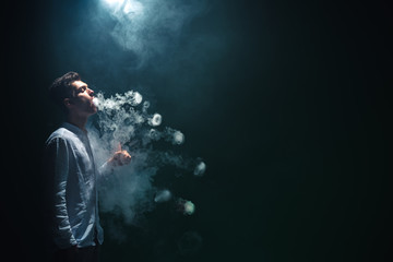 The man smoke an electrical cigarette with a ring and on the dark background