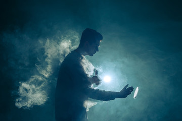 The man smoke an electronic cigarette with a ring on the bright light background