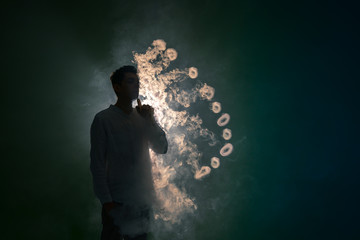 The man smoke an electronic cigarette with a ring against the background of the dark light