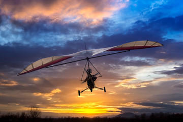 Fototapeta na wymiar Motorized hang glider flying in the sunset