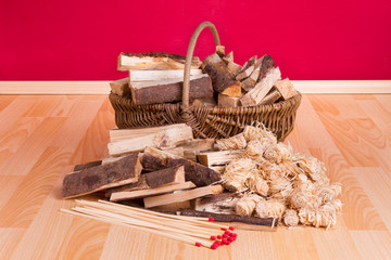 Korb mit Anzündholz und Streihölzern auf dunklem Parkett