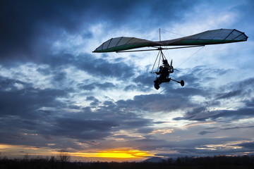 Motorized hang glider flying in the sunset