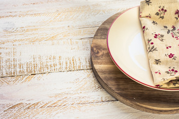 Off-white empty plate with red board on round cutting board, linen floral napkin, white plank wood background, Provence style, kitchen interior, minimalistic, kinfolk,top angle view