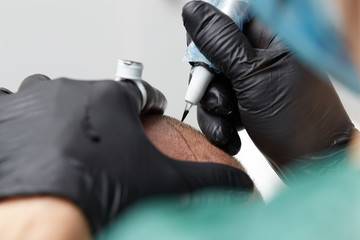 Cosmetologist making permanent makeup on man head - tricopigmentation