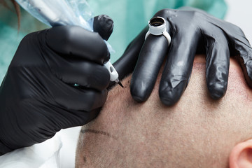 Cosmetologist making permanent makeup on man head - tricopigmentation