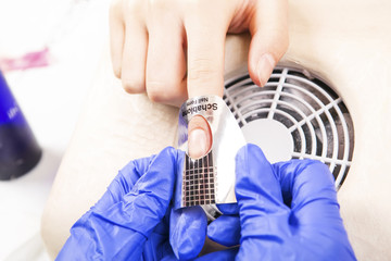 Manicure specialist care by finger nail in beauty salon. Manicurist uses professional manicure...