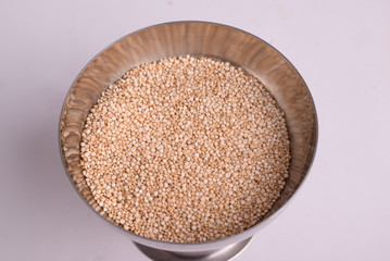 Quinoa seeds in a bowl on grey background