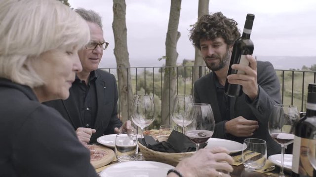 Parents with grown-up son dining outdoors