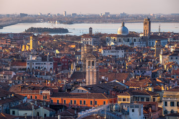 Aerial view of Venice, Italy, at sunset with rooftops of building, the sea and warm sunlight.