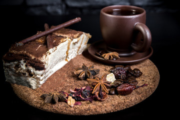 Cup of coffee and ground coffee beans. Delicious tiramisu dessert with cocoa powder isolated on black background. Traditional sweet dessert.