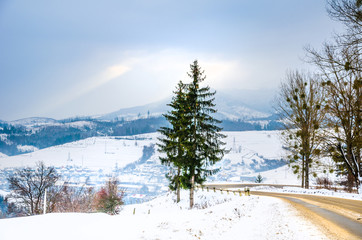 Winter landscape, snow covered road in the mountains with trees