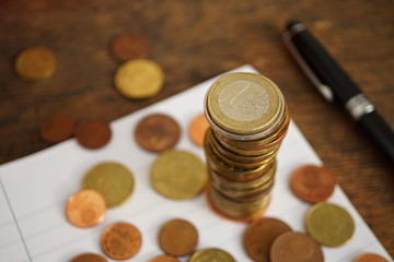Macro money background made of column of Euro coins on the lined paper notebook with many coins of various value below as a symbol of European finances