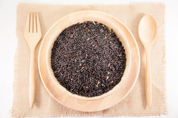 The Organic rice in wooden bowl with Wooden spoon and fork. The purple rice organic in wooden bowl.