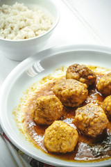 Homemade Meatballs in curry sauce and white rice on rustic backg