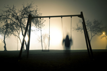 Man on the swing in foggy and mysterious park at night - 134020610