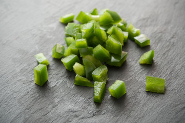 poivrons vert coupés en cubes sur ardoise