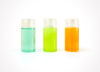 Three small plastic bottles full of colorful cosmetic products with copy space