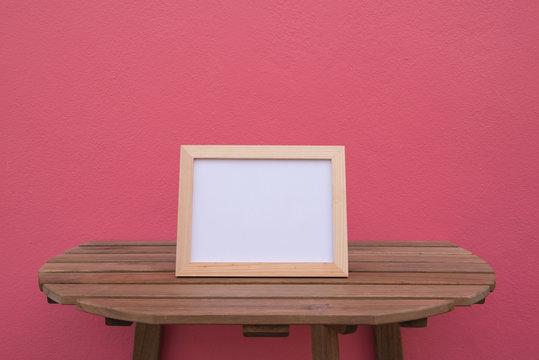 photo Frame on a wooden on pink background .