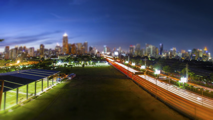 Obraz premium Road through the Bangkok city business area in the evening blue sky, tilt-shift effect background