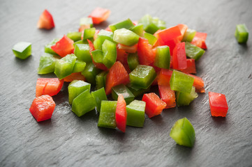 poivrons rouge et vert coupés en cubes sur ardoise