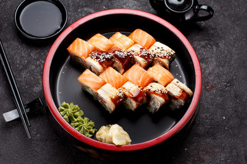 Japanese cuisine. Sushi roll set on a round wooden plate and dark concrete background.