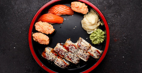 Japanese cuisine. Sushi roll set on a round wooden plate and dark concrete background.