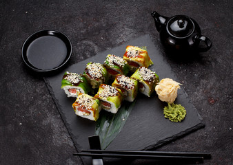 Japanese cuisine. Sushi set on a stone plate and concrete background.