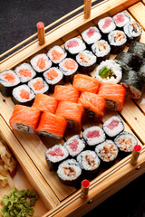 Japanese cuisine. Sushi set on a wooden plate and dark concrete background.