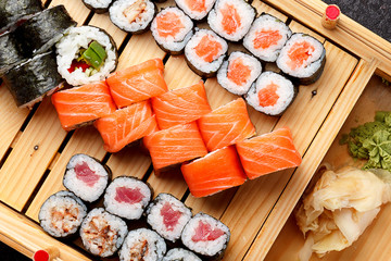 Japanese cuisine. Sushi set on a wooden plate and dark concrete background.