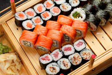 Japanese cuisine. Sushi set on a wooden plate and dark concrete background.