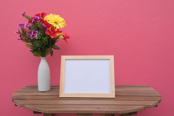 photo Frame on a wooden and Flowers in jar on pink background .