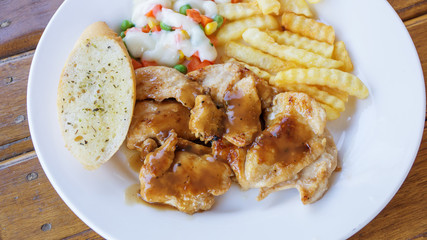 chicken steak with french fries, bread, and salad.