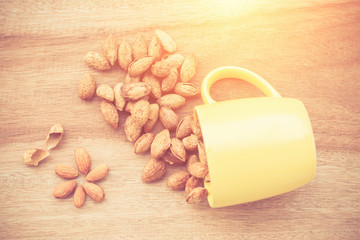 Almonds in yellow bowl on wooden background