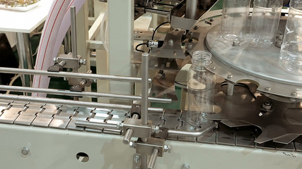 Bottling conveyor product line for pouring beverages into plastic bottles. Robotics and automatic lines instead of human labor on factories and plants.