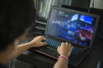 Image of blurred back head view of concentrated Asian Gamer playing game at home