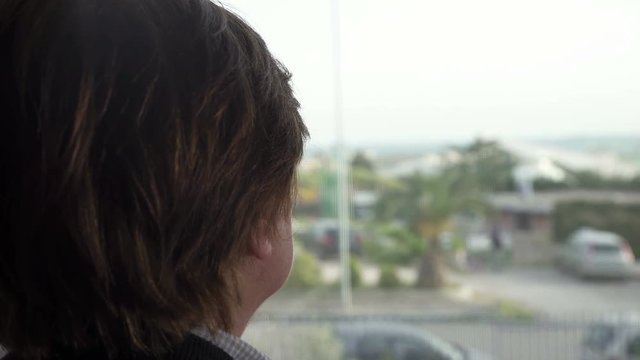 woman with short hair from the back looks out the window