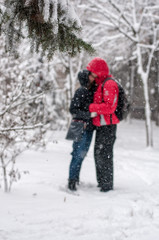 Young couple in love kissing outdoors in snowy winter
