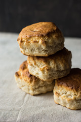 Pile of homemade fresh English scones on a table covered with linen cloth, dark background, minimalistic kitchen interior, kinfolk
