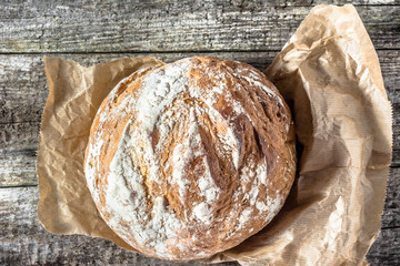 Fresh baked bread loaf on rustic wooden table, baking concept