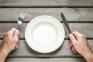 Hungry man waiting for his meal over empty plate