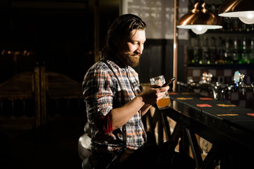 a bearded man looking smartphone and keep a glass of beer
